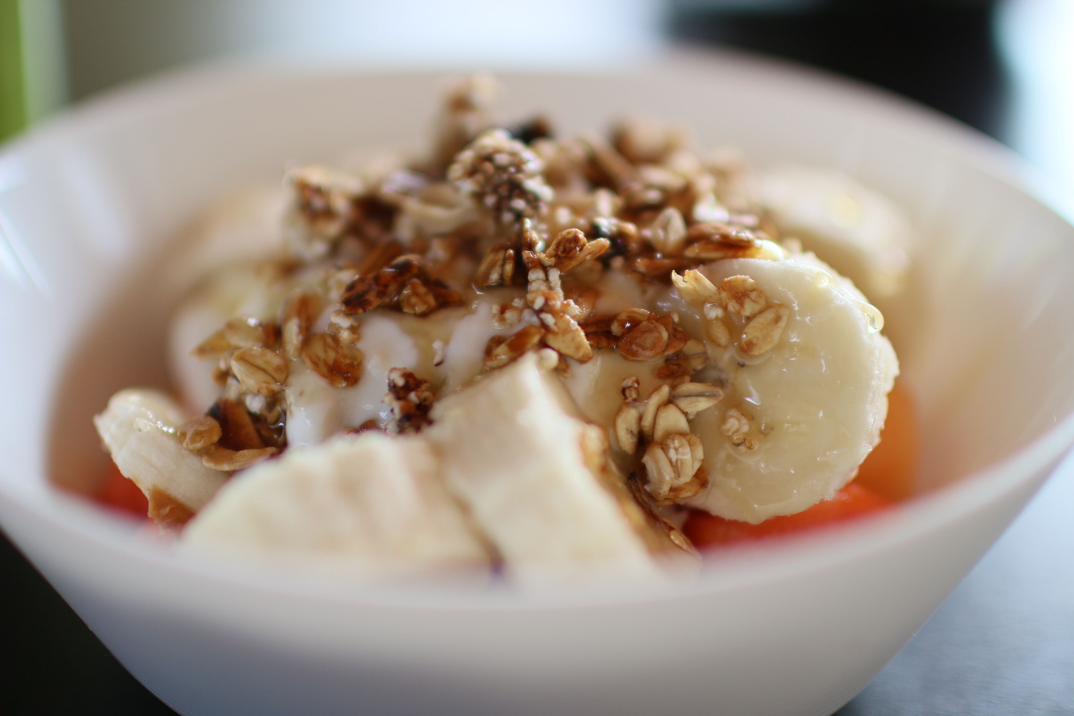 A bowl of food with bananas and granola.