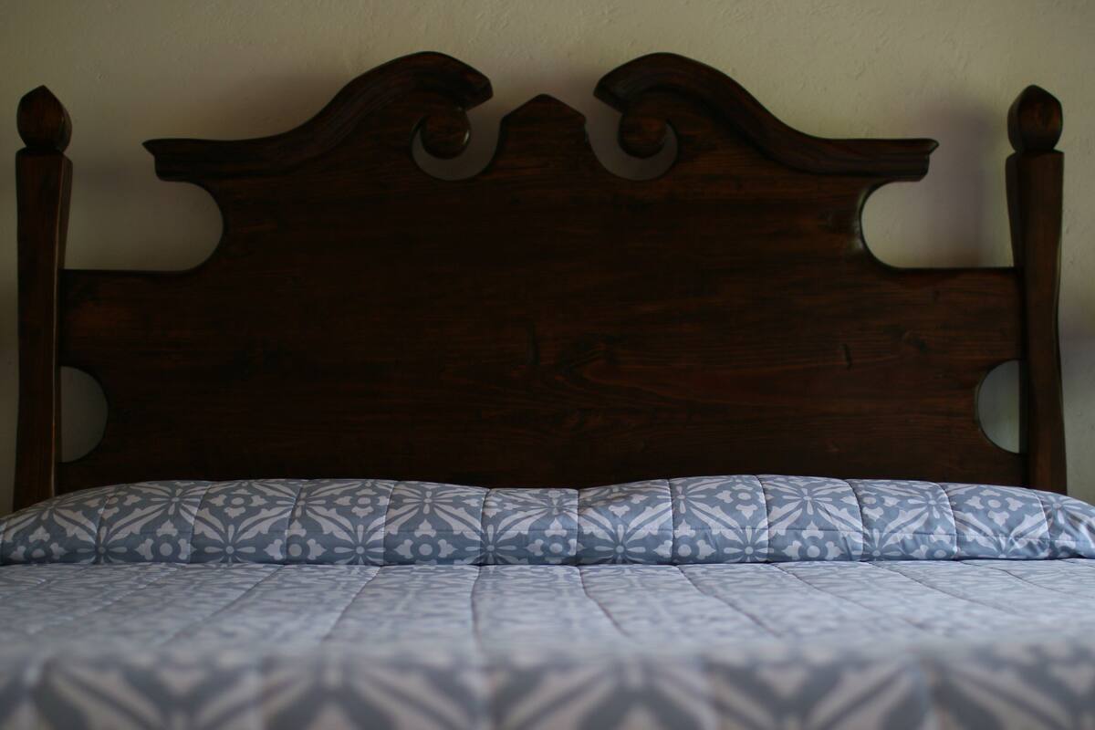 A wooden headboard with a carved design and a patterned bedspread.