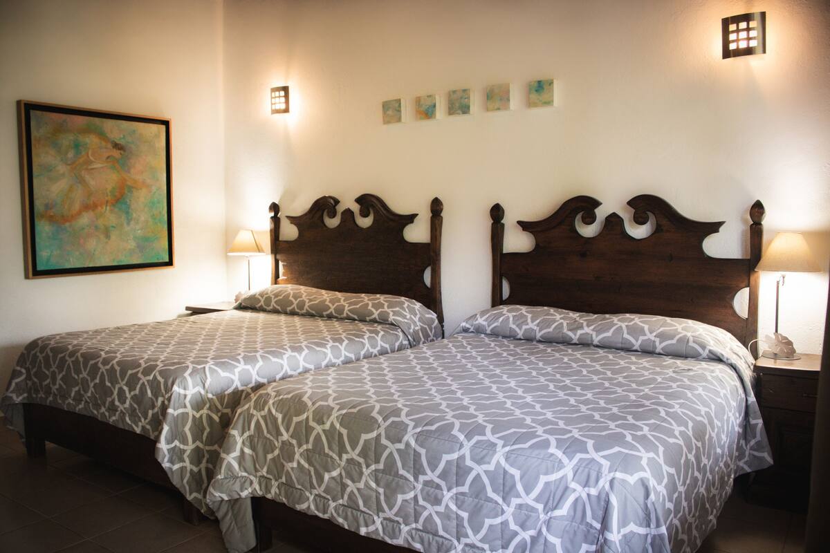 A double bed with a patterned bedspread, two bedside tables with lamps, and a wall-mounted artwork.