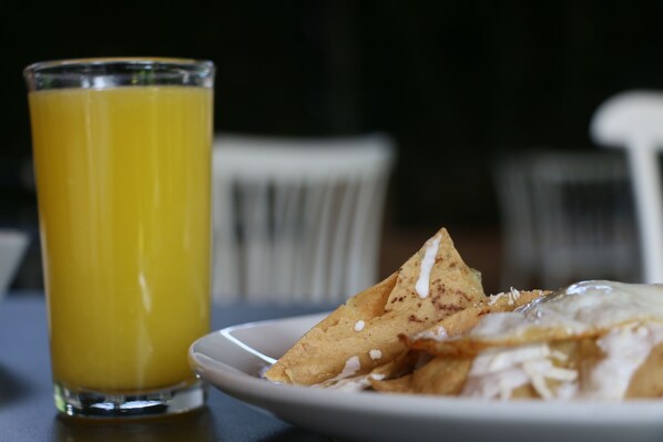 A plate of nachos with cheese and a glass of orange juice on a table. - Hotel Posada La Presa (Tepoztlán)