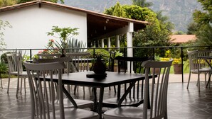 An outdoor patio with a table and chairs, surrounded by potted plants and a view of a mountain. - Hotel Posada La Presa (Tepoztlán)