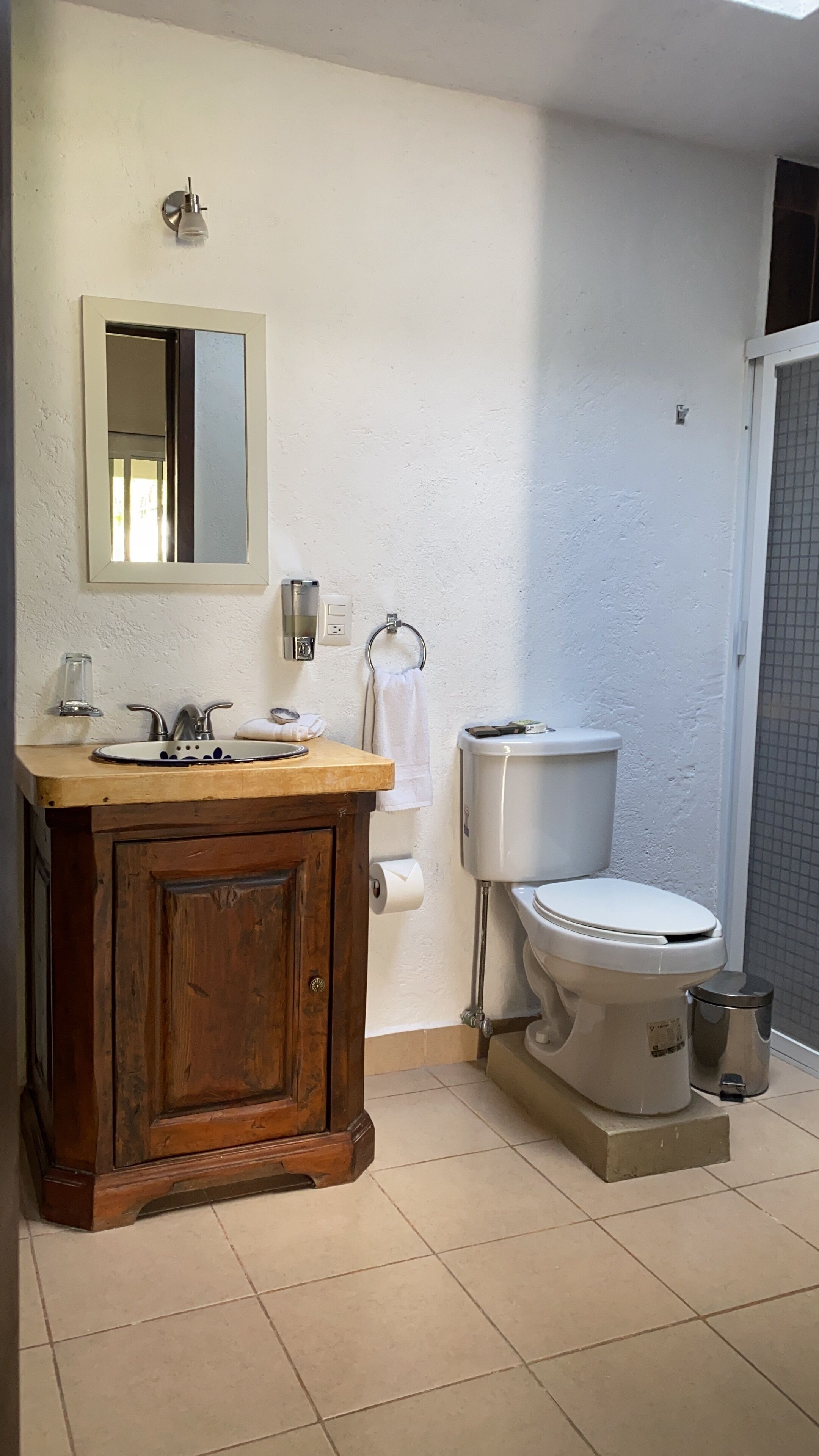 A bathroom with a wooden vanity, a toilet, a bidet, and a mirror.