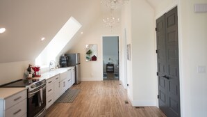 A modern kitchen with a skylight, a chandelier, and a view into the living area. - "The Primm Loft" Private, Spacious, Clean & New (Murfreesboro)