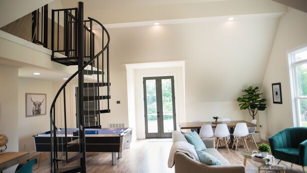A spacious living area with a spiral staircase, a dining table with chairs, a sofa, and a green armchair. - "The Primm Loft" Private, Spacious, Clean & New (Murfreesboro)