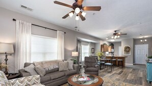 Ein geräumiges Wohnzimmer mit einer Couch, Sesseln, einem Couchtisch und einem Essbereich mit Stühlen und Tisch.
