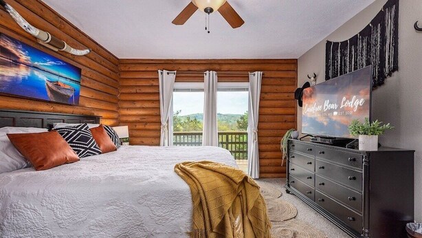 A bedroom with a large bed, a ceiling fan, a TV, and a view of the outdoors. - Lakefront! Hot Tub-Fire Pit, game room, paddle boards & canoe! (Kimberling City)