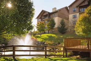 Relax on the serene lawn, surrounded by a tranquil pond and lush trees.