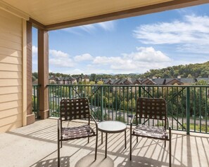 Enjoy the view from this balcony with a small table and two chairs.