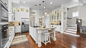A modern kitchen with white cabinetry, a central island, and a wooden floor. - "116 Surfer Ln" | Resort Style Community Pool | Walk to Rosemary Beach (Seacrest Beach)