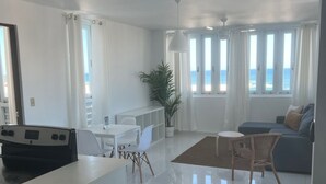 A modern living room with a dining area, a kitchen, and a view of the sea. - Arecibo Hotel 4301 (Arecibo)