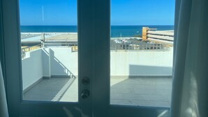 A view from a balcony with a clear blue sky, a beach, and a parking area. - Arecibo Hotel 4301 (Arecibo)
