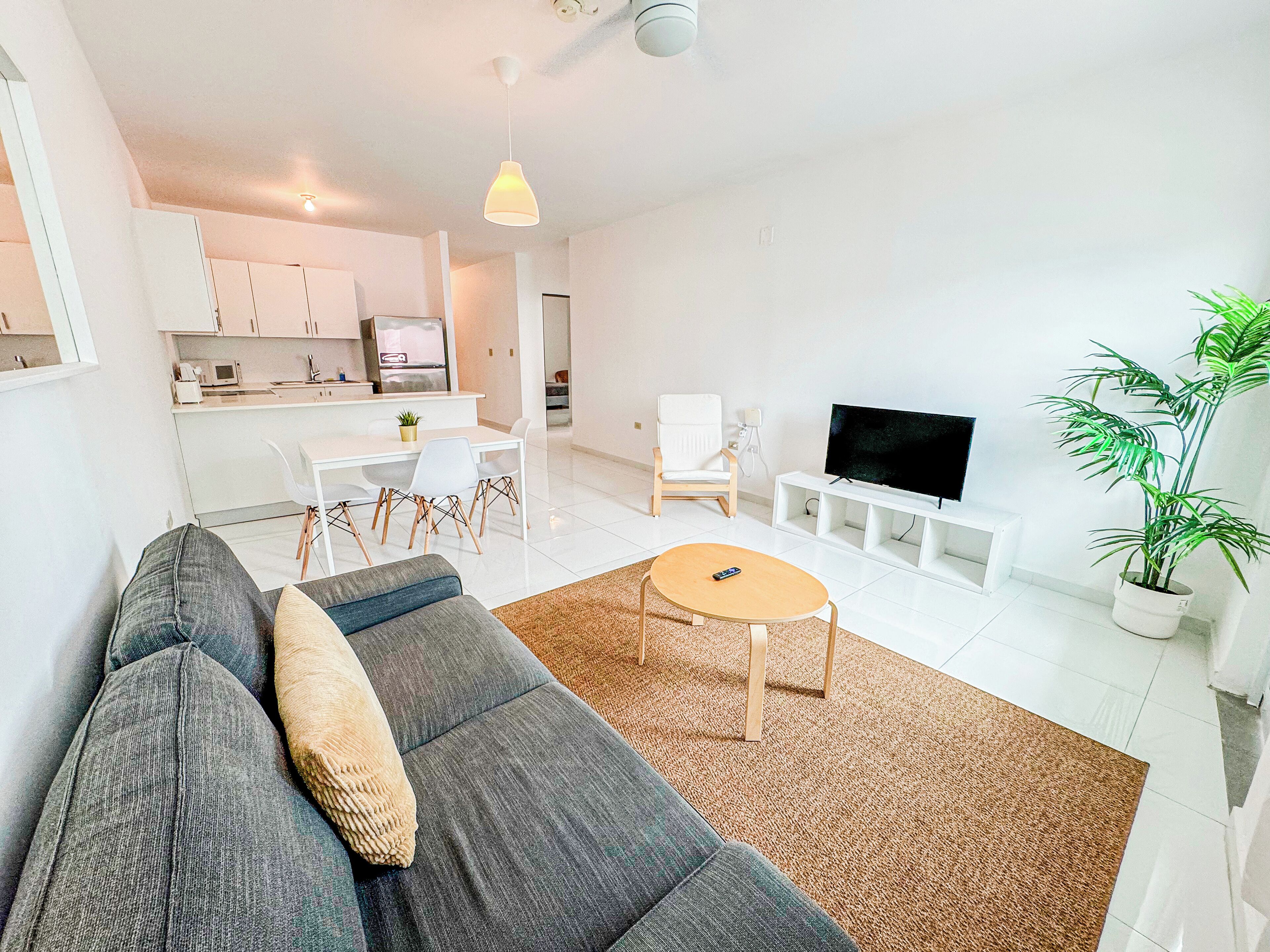 A modern living room with a grey sofa, a coffee table, and a TV stand.