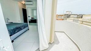 A balcony with a view of the city, a bed with a blue cover, and a white curtain. - Arecibo Hotel 3202 (Arecibo)