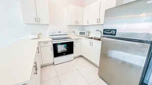 A modern kitchen with white cabinets, a stainless steel refrigerator, a microwave, and an oven. - Arecibo Hotel 3202 (Arecibo)