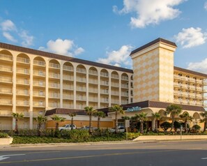 Ein mehrstöckiges Hotel mit Innenhof, Balkonen und Palmen.