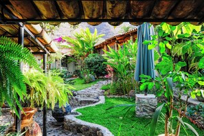 Un exuberante jardín con un sendero de piedra, plantas en macetas y una estructura de pérgola de madera.