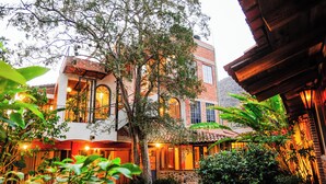 A traditional building with a stone courtyard, large windows, and a tree in the center. - Casa Aurora Garden Retreat (Ajijic)