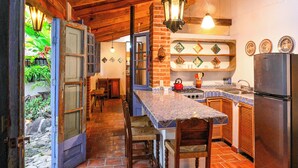 A rustic kitchen with a stone floor, wooden beams, a gas stove, and a refrigerator. - Casa Aurora Garden Retreat (Ajijic)