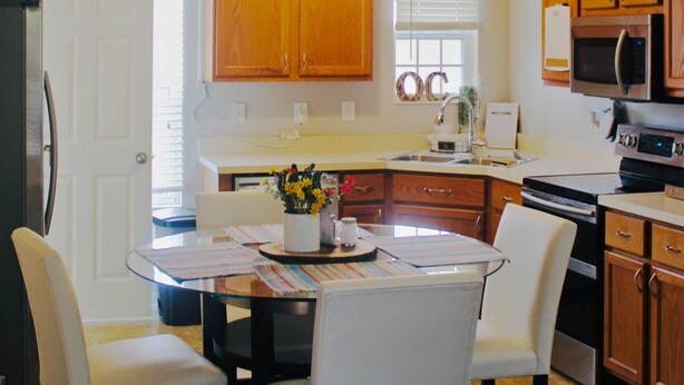 A compact kitchen with wooden cabinets, a microwave, and a refrigerator.