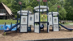 A playground with a castle-like play structure, a slide, and a swing set.