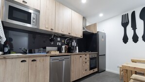 A modern kitchen with wooden cabinets, stainless steel appliances, and a black refrigerator. - Coimbra City Charm (Coimbra)