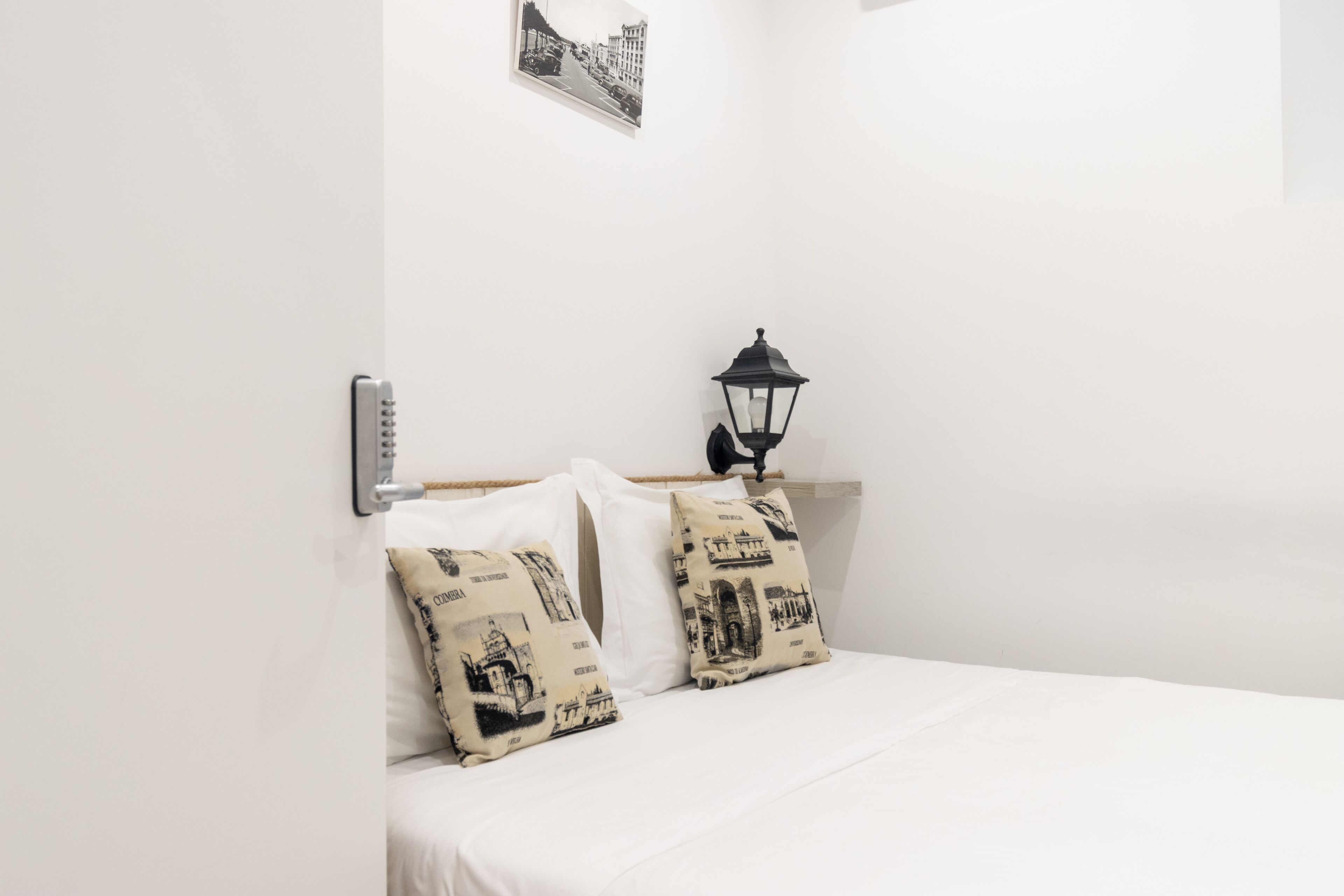 A bed with white bedding and two decorative pillows with black and white prints.