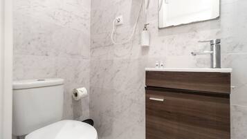 A modern bathroom with a toilet, a shower, and a vanity with a sink.
