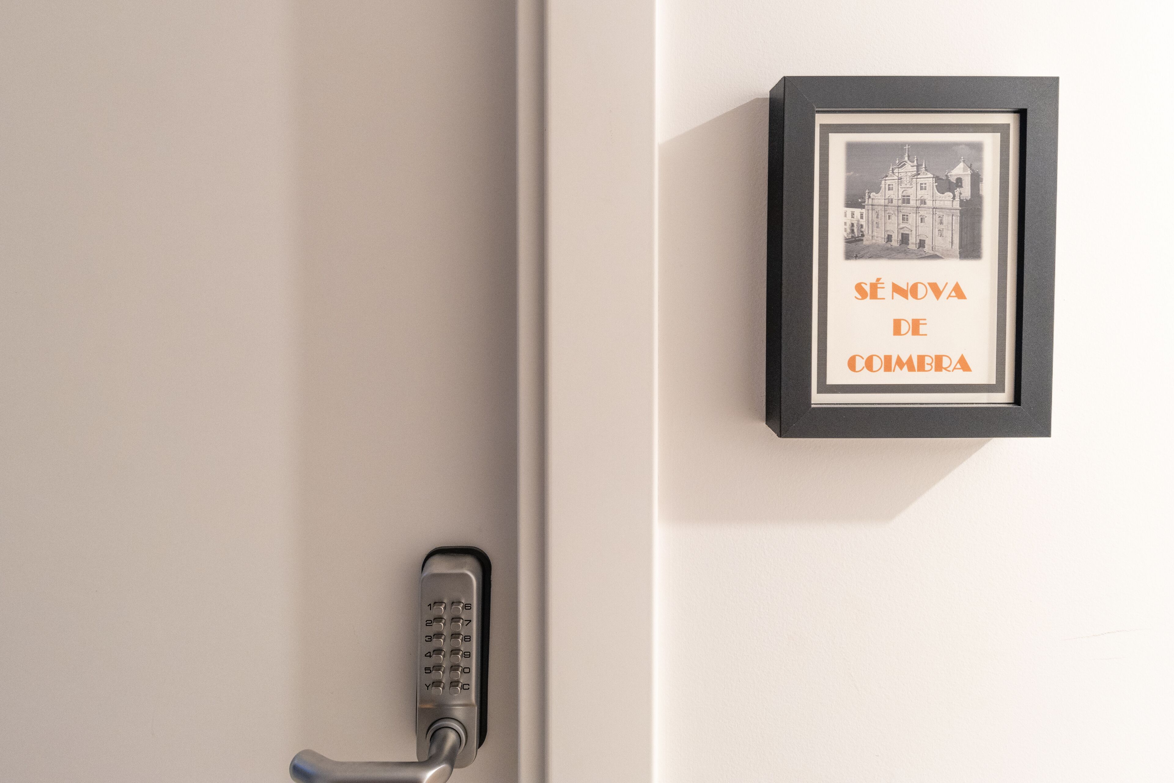 Eine Tür mit Zahlenschloss und einem gerahmten Bild an der Wand.