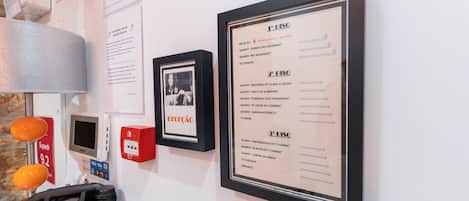 A reception area with a framed menu, a payphone, and a digital payment terminal.