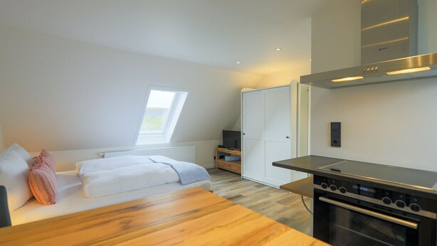 A modern kitchen with a built-in oven and a dining area with a wooden table.