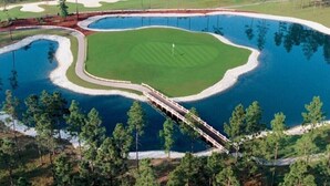 A golf course with a water hazard, a bridge, and surrounding trees. - Calm Retreat or Golf Getaway! Close to Local  Attractions. (Calabash)