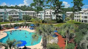 A resort with multiple-story buildings, a central swimming pool, and surrounding palm trees. - Calm Retreat or Golf Getaway! Close to Local  Attractions. (Calabash)