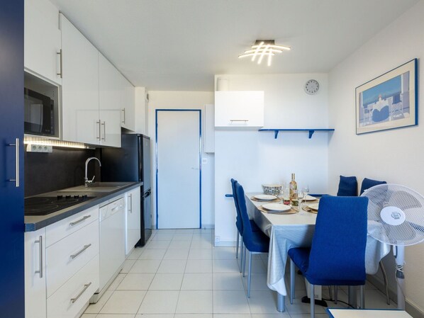 A modern kitchen with white cabinets, a black stove, and a dining area with a table set for two.