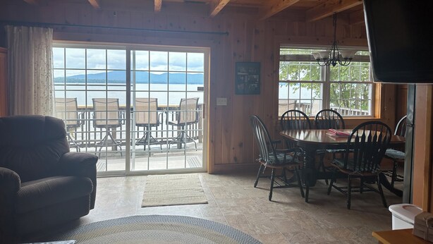 A cozy cabin interior with a dining area, a sofa, and a ceiling fan.