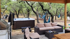 Ein Außenbereich mit Terrasse, Whirlpool, Korbmöbeln und Pool.