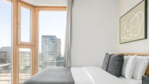A modern bedroom with a large bed, a city view, and a contemporary abstract painting. - Lovely Favoriten 3BR w/ Roof, Gym & Lounge, 1min to HBF, by Blueground (Vienna)