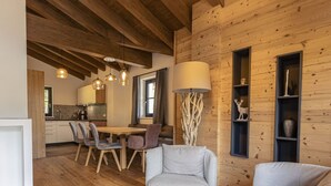 A cozy interior with wooden walls, a dining area with chairs, a sofa, and a lamp. - Nice apartment for 10 guests with WIFI, TV, terrace and panoramic view (Brandstätter)