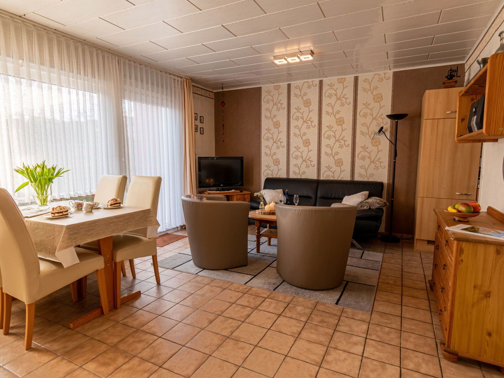 Una sala de estar con una mesa de comedor, sillas, un sofá, un televisor y un mueble.