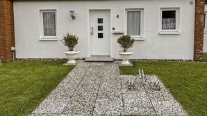 A modern two-story building with a white facade, a brick chimney, and a gravel driveway leading to a white door. - Stunning  villa for 4 people with TV and terrace (Norden)