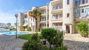 Un hotel de varios pisos con piscina, pilares de piedra y balcones.