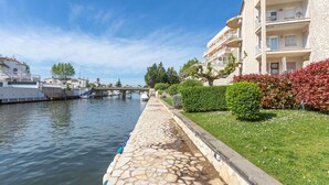 Un canal con barcos, un camino de piedra y un edificio con balcones.