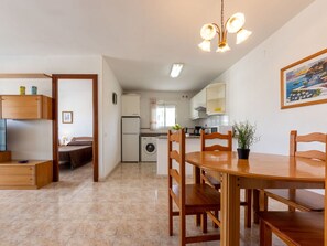 Cozinha compacta com área de refeições, máquina de lavar e pequena geladeira.