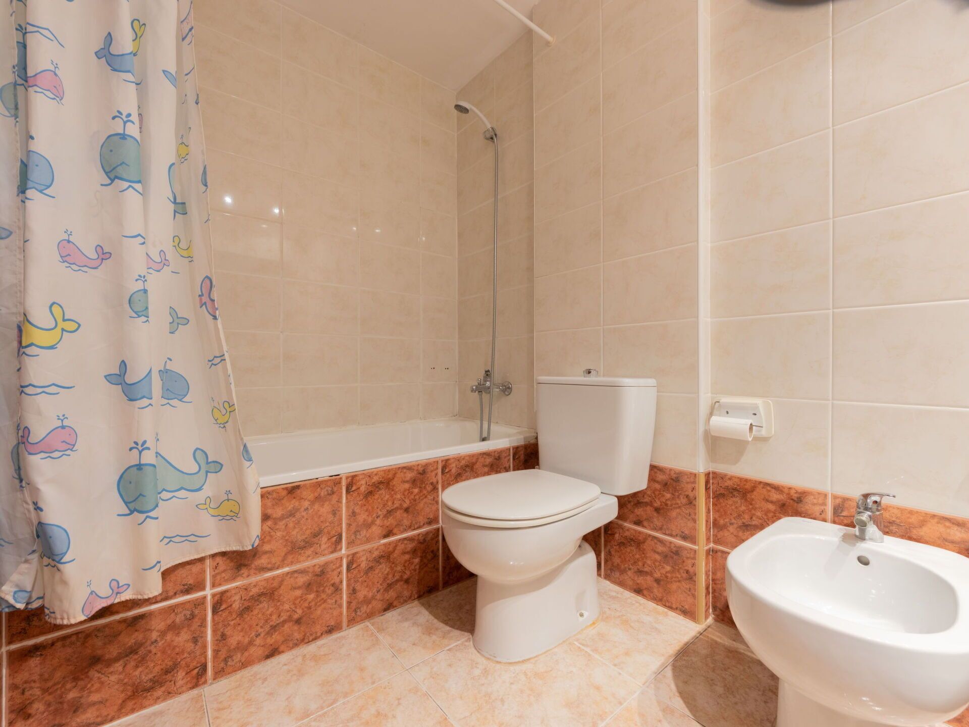 A bathroom with a bathtub, toilet, and bidet.