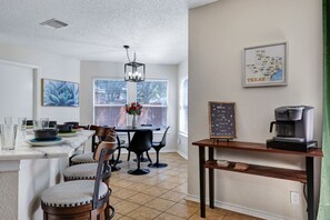 A modern kitchen with a dining area, a coffee station, and a map of Texas on the wall. - Pet Friendly 5 Bedroom Home (San Antonio)