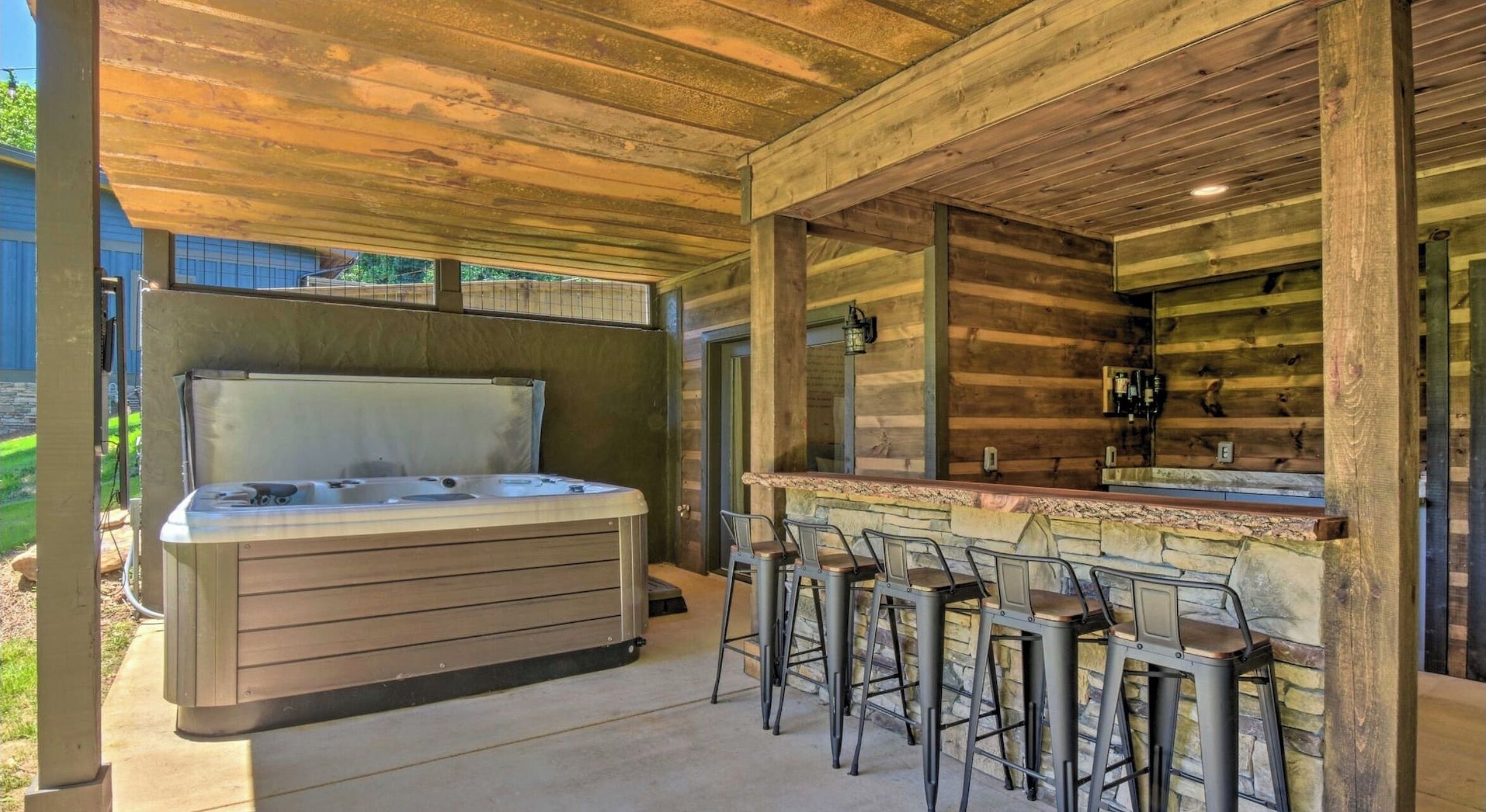 An outdoor hot tub area with a stone bar and metal chairs.