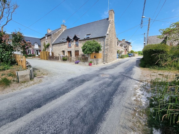 A rural road with stone houses, a wooden fence, and a clear blue sky.