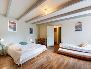 Ein Zimmer mit zwei Betten, Holzboden und einer Tür zu einem weiteren Raum.