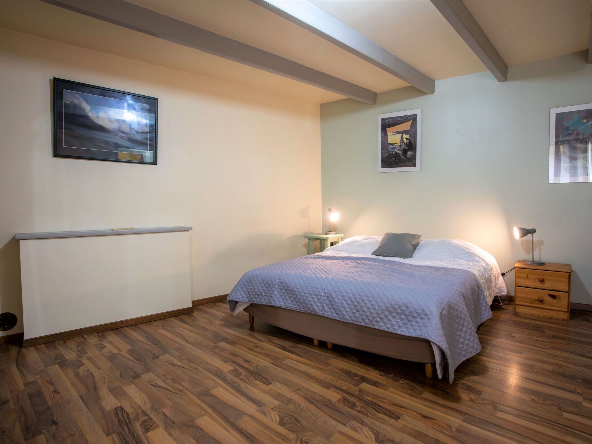 A bedroom with a bed, bedside tables, and a radiator.