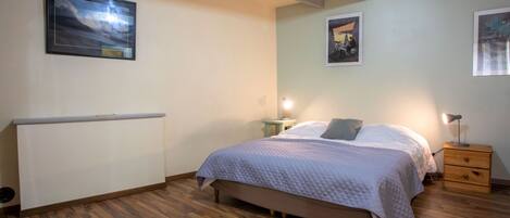A bedroom with a bed, bedside tables, and a radiator.