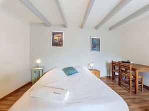 Una camera da letto con un letto, una scrivania e due quadri appesi al muro.